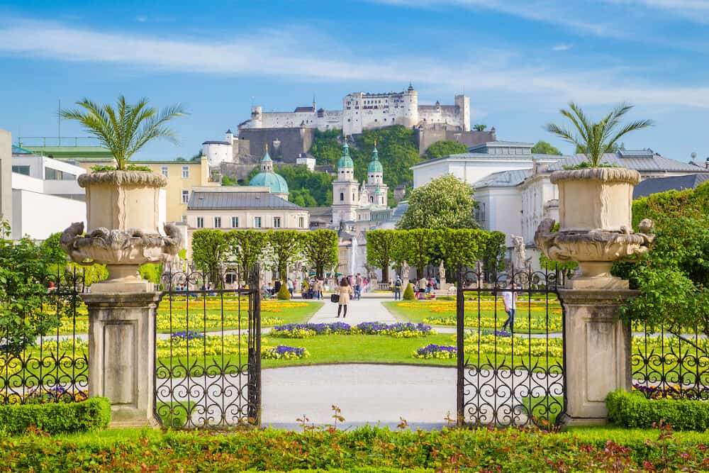 Classic view of famous Mirabell Gardens with the old historic Fortress Hohensalzburg in the background on a beautiful sunny day with blue sky and clouds in summer in Salzburg Austria