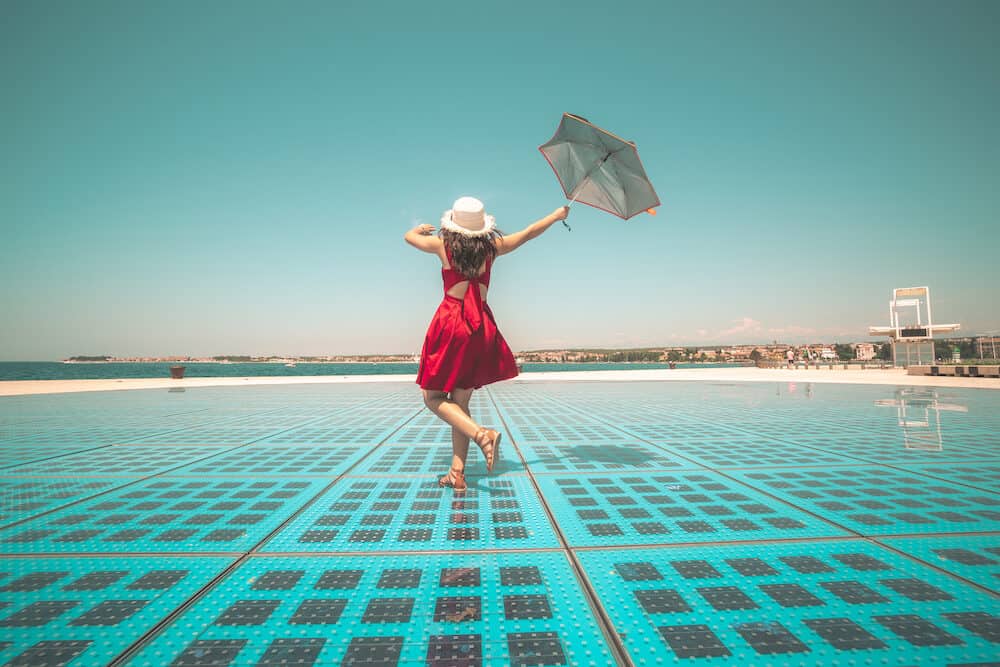 Happy woman traveler dances on outdoor disco floor in Zadar, Croatia.