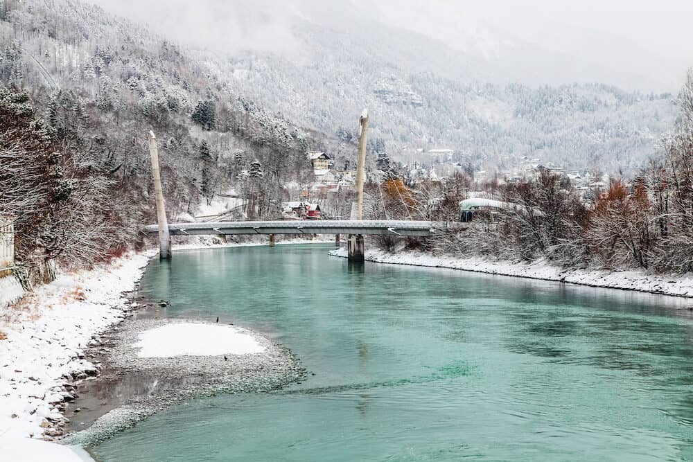 Beautiful Innsbruck with river Inn on snow winter day. Magic color of water.