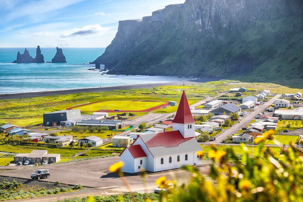 Breathtaking view of Vikurkirkja christian church in blooming flowers. Most popular tourist destination. Location: Vik village in Myrdal Valley, Iceland, Europe.