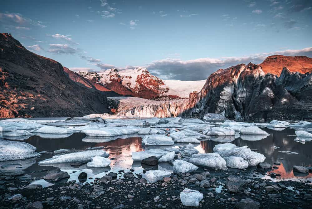 Warm sunlight across the ice and mountains of Svinafellsjokul glacier at sunset, southern iceland. Part of the larger Vatnajokull glacier, the largest ice cap in iceland. Dark and moody processing.